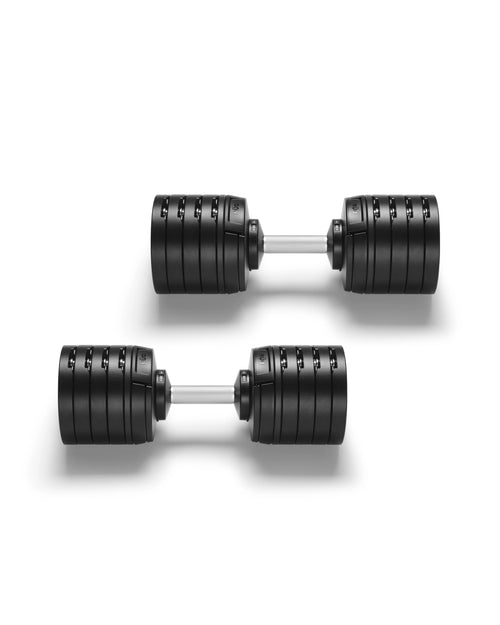Pair of NÜOBELL S 240 adjustable dumbbells in matte black photographed from directly above on a white background, showing the symmetrical four-plate rotating construction on each end, the brushed aluminum handles with machined knurling, and the compact parallel arrangement that demonstrates the space-efficient design replacing 20 pairs of fixed weights.